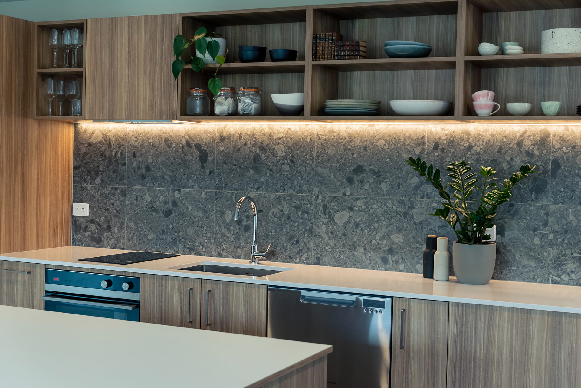 Full shot of apartment kitchen with tap, bentop and cabinetry